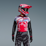 Tenue Techstar Beast Coast Édition Limitée, maillot rouge et bleu, pantalon camouflage gris, casque rose et masque noir.