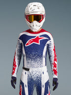 Maillot Alpinestars Techstar Unity, maillot de motocross édition limitée rouge, blanc et bleu, coupe athlétique sur un pilote.