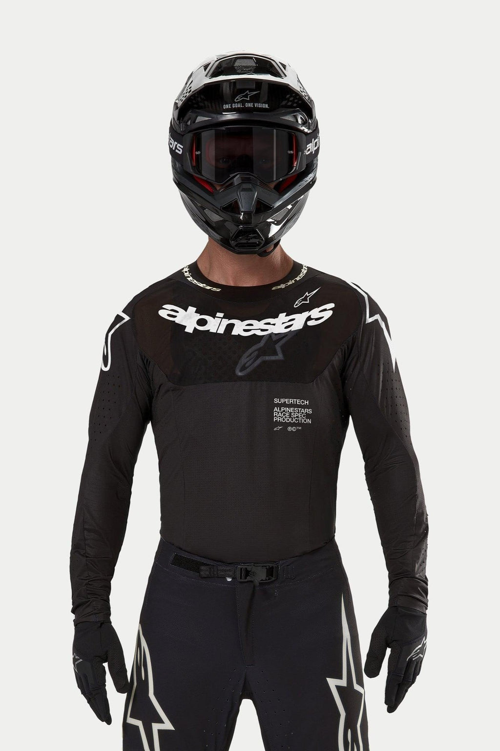Motocross-Fahrer im Alpinestars 2024 Supertech Ward Jersey in Schwarz, athletische Rennpassform mit weißem Alpinestars-Logo auf der Brust, lasergeschnittenen Perforationen und 'Supertech Race Spec'-Schriftzug, kombiniert mit schwarzem Helm und Brille für den Offroad-Rennsport.