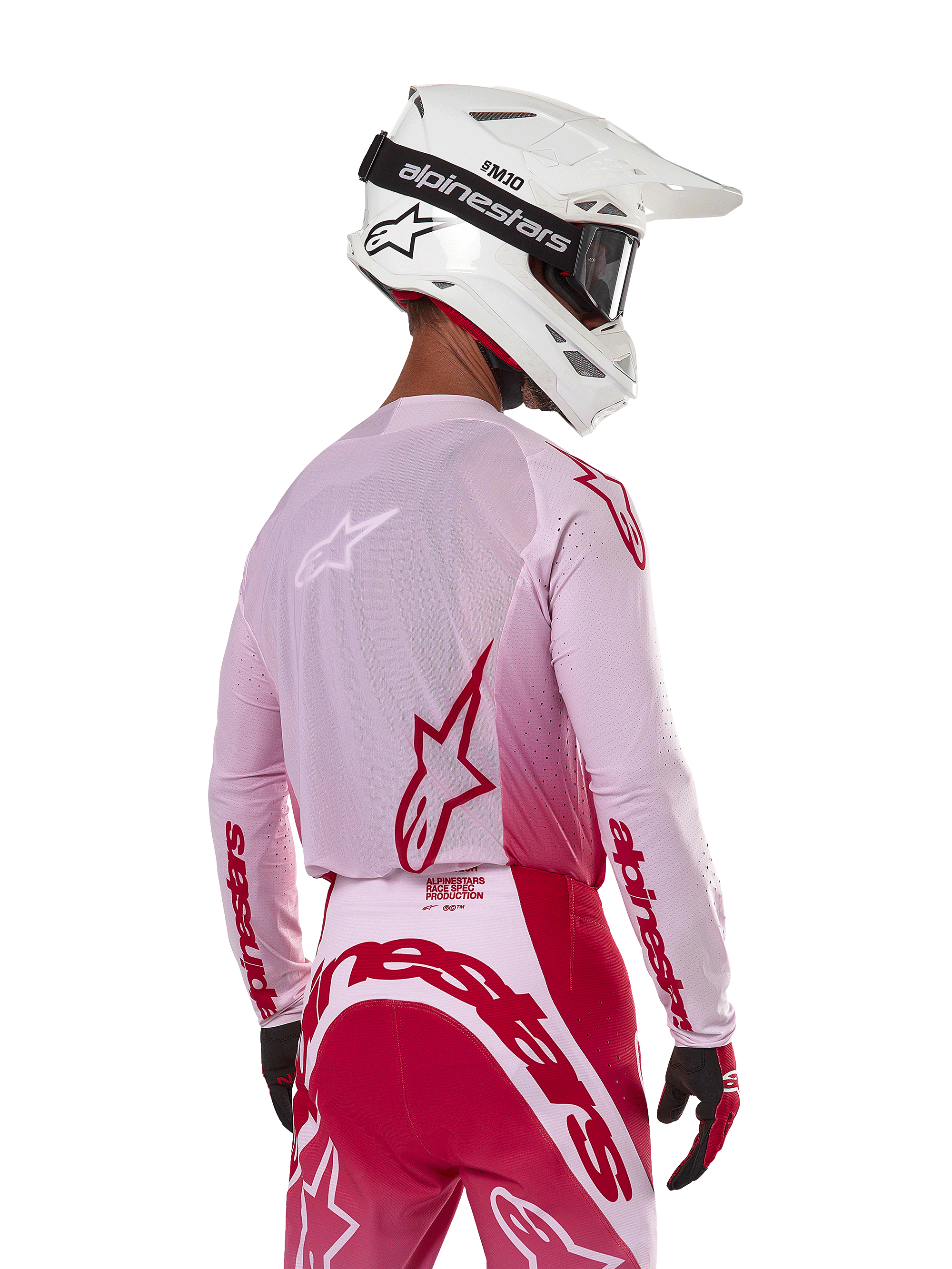 Motocross-Fahrer in der Rückansicht, trägt das Alpinestars 2024 Supertech Dade Jersey in Red Berry Lilac, mit atmungsaktiven Mesh-Panels und roten Alpinestars-Logos, kombiniert mit einer passenden rot-lilafarbenen Hose und einem weißen Alpinestars-Helm mit Brille, professionelle Offroad-Rennausrüstung