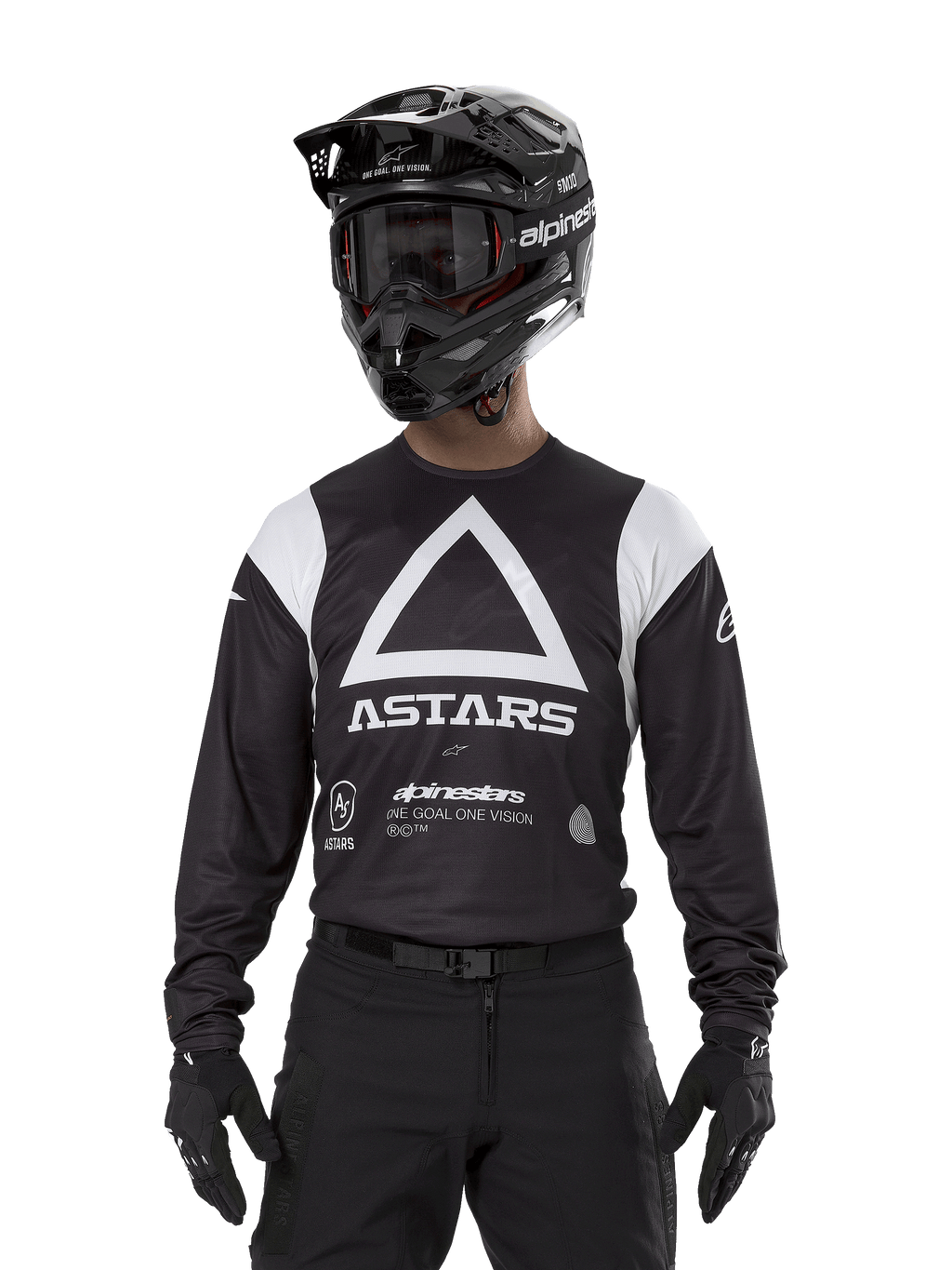 Maillot Alpinestars Techdura, noir, arborant un grand motif triangulaire blanc sur la poitrine avec le logo ASTARS et des empiècements blancs aux épaules, porté par un pilote avec un casque de motocross noir, des lunettes et une tenue tout-terrain noire assortie.