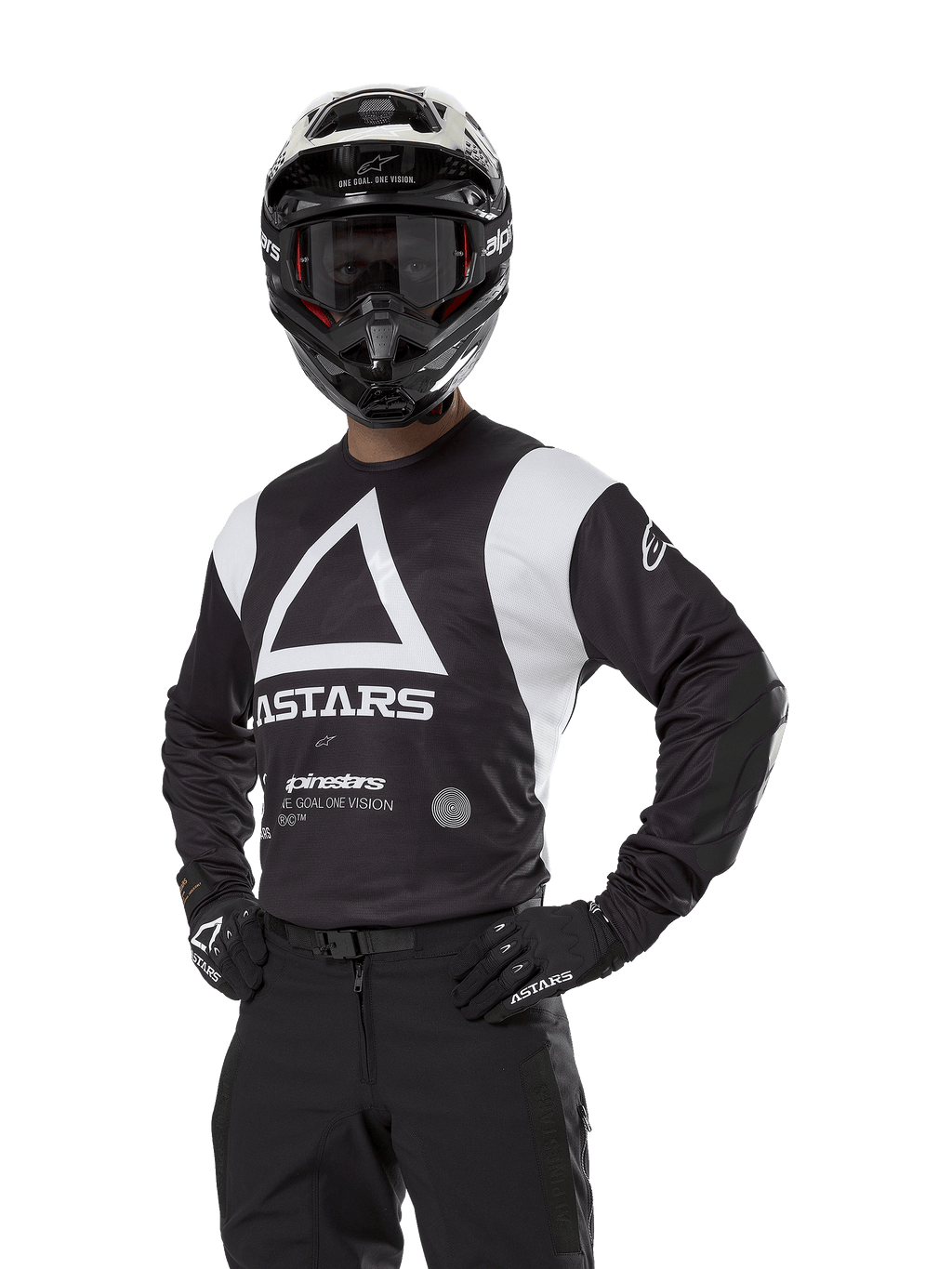 Maillot Alpinestars Techdura, maillot de motocross, noir et blanc, porté avec casque et gants assortis, pose les mains sur les hanches sur fond blanc, avec un grand logo A triangulaire et le marquage ASTARS
