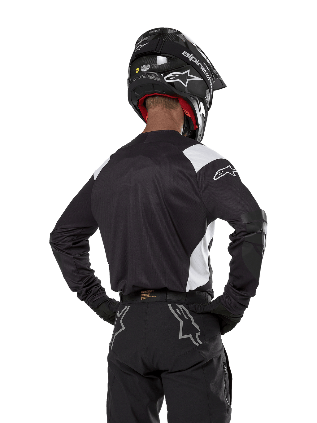 Maillot Alpinestars Techdura, noir avec accents blancs sur les épaules, vue de dos d'un pilote de motocross portant un pantalon et un casque noirs assortis, renforts aux coudes, équipement de course enduro et tout-terrain