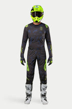 Ensemble maillot et pantalon Alpinestars Techstar Rantera 2024, tenue de motocross, noir, bleu marine et jaune fluo, porté avec un casque jaune fluo assorti et des bottes blanches, avec logos jaunes vifs et panneaux en maille technique pour la performance tout-terrain