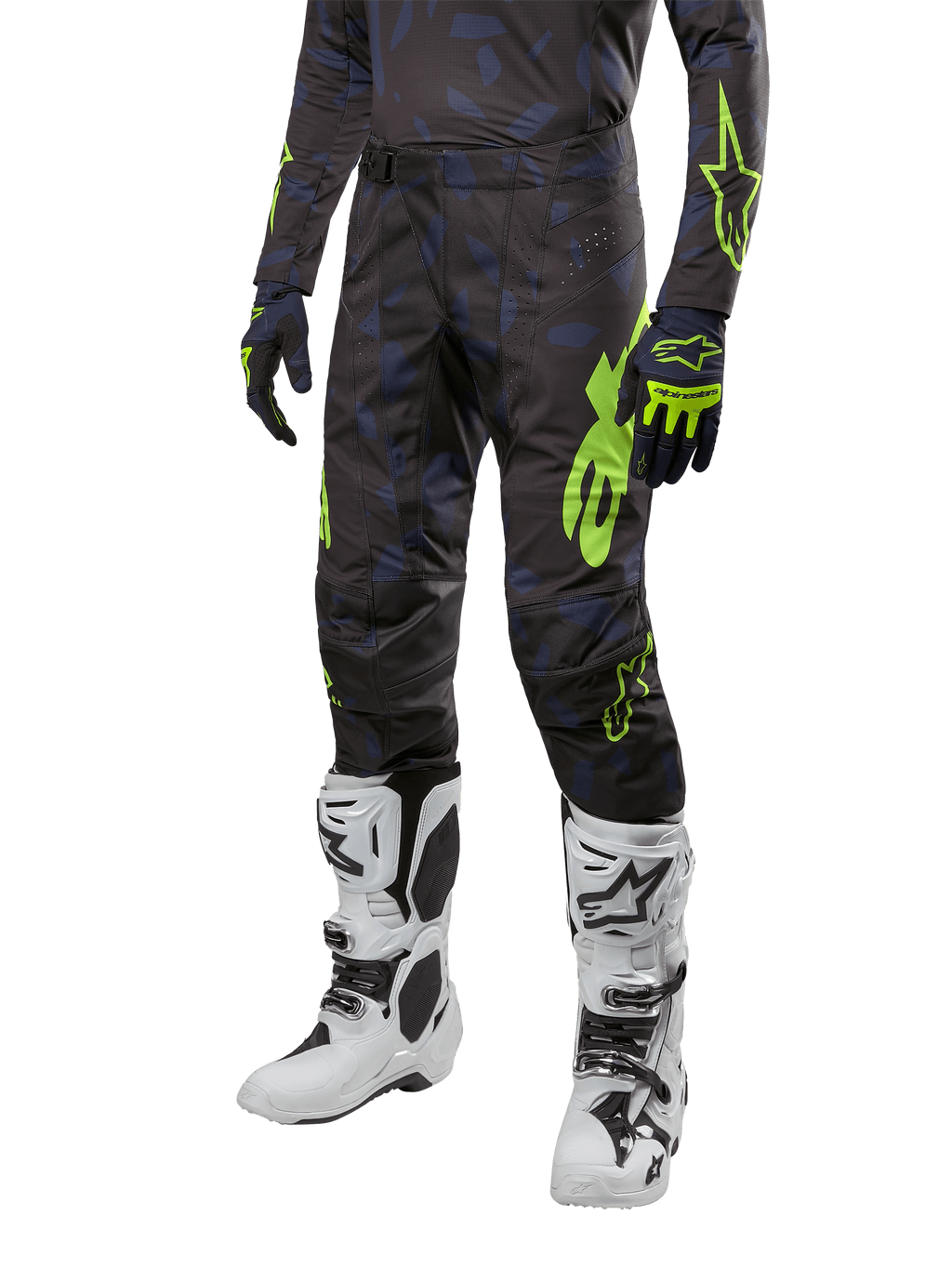 Pantalon Alpinestars Techstar Rantera 2024, pantalon de motocross, noir, bleu marine et jaune fluo, avec motifs camouflage bleu marine et logos vert néon, porté avec des gants assortis et des bottes blanches, coupe racing durable pour la performance tout-terrain