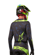 Vue arrière d'un pilote de motocross portant le maillot Alpinestars Techstar Rantera 2024 en Noir Marine Jaune Fluo, avec des logos jaune fluo proéminents au dos, associé à un pantalon de motocross assorti et un casque jaune fluo pour un look de course tout-terrain complet.