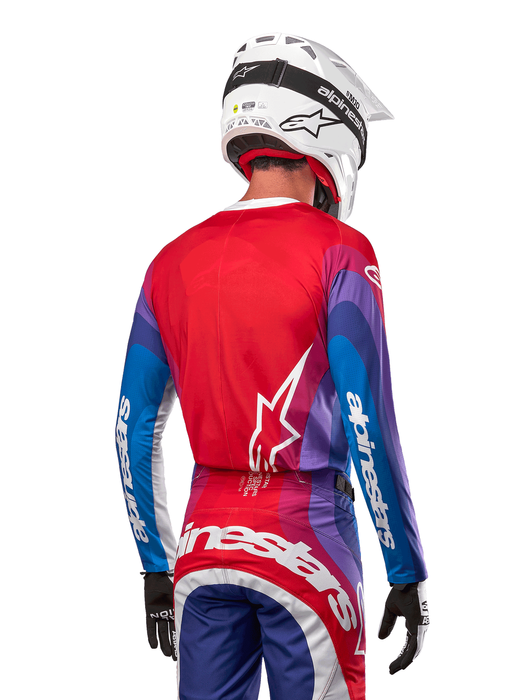 Motorcrosser van achteren gezien in Alpinestars 2024 Techstar Pneuma Jersey in Blue Mars Red White, met een rode rug met wit sterlogo, blauwe en paarse mouwen met witte branding, gecombineerd met bijpassende broek en een witte helm voor off-road racing.