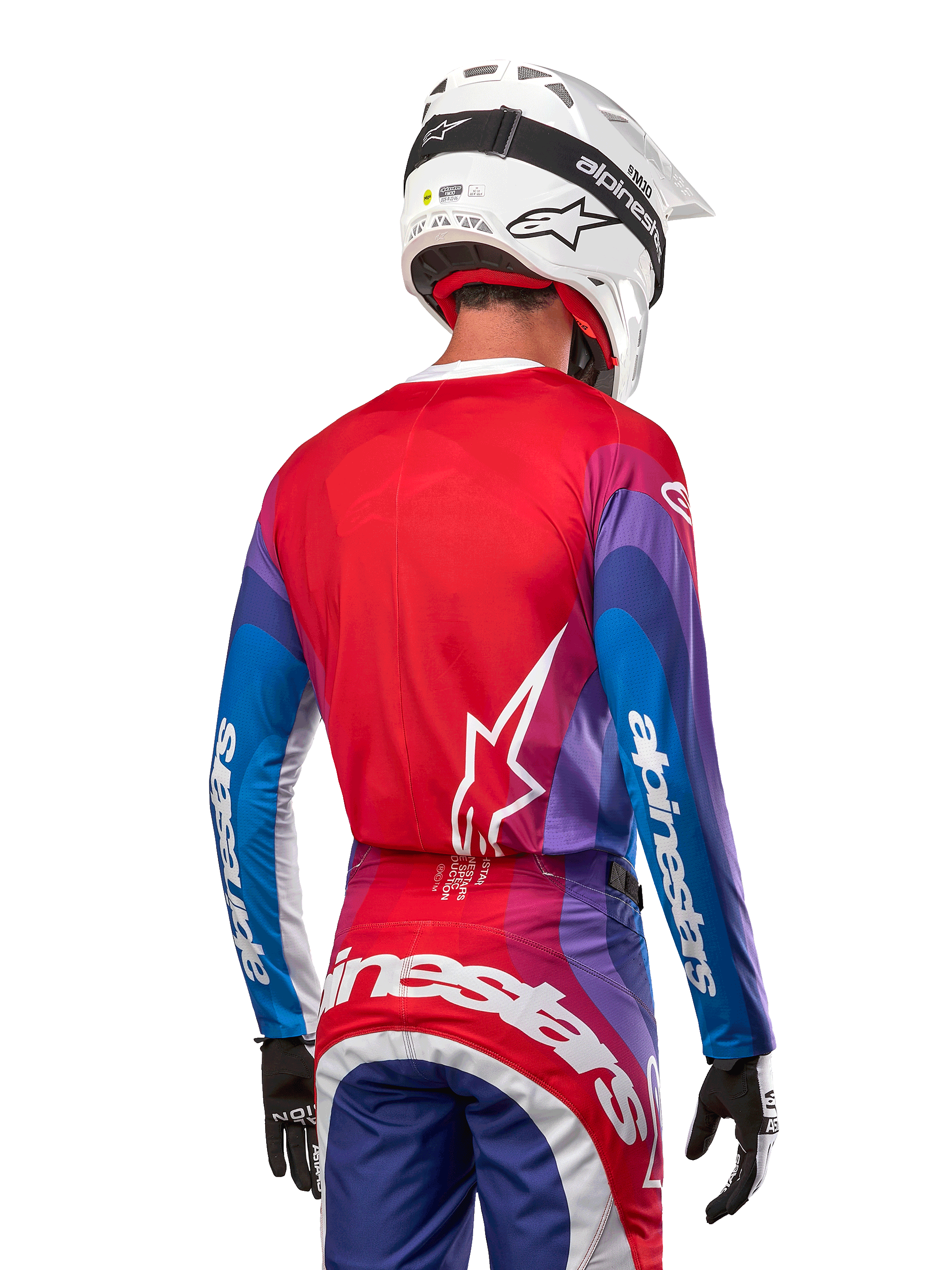 Motorcrosser van achteren gezien in Alpinestars 2024 Techstar Pneuma Jersey in Blue Mars Red White, met een rode rug met wit sterlogo, blauwe en paarse mouwen met witte branding, gecombineerd met bijpassende broek en een witte helm voor off-road racing.