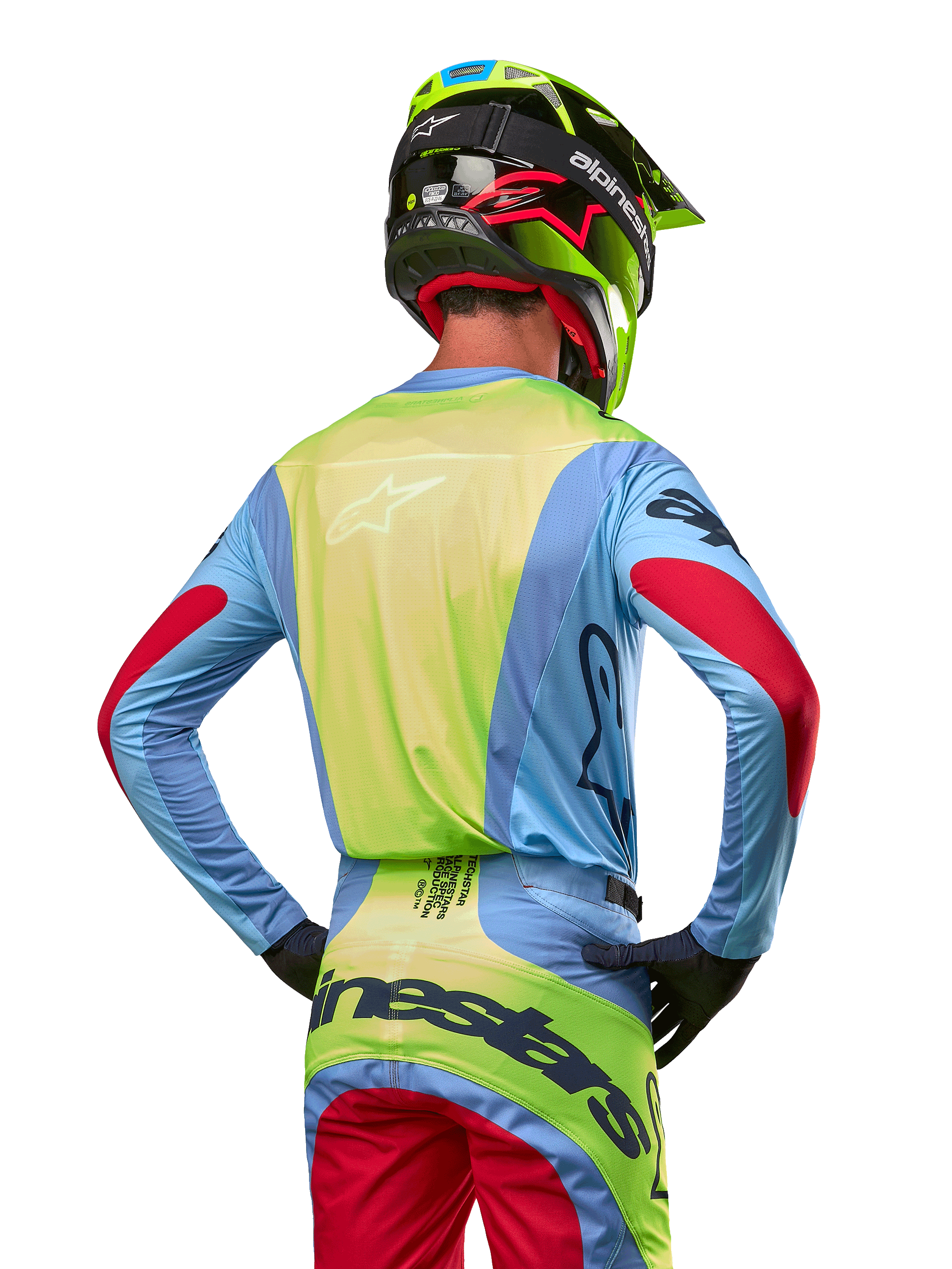 Motocrosser van achteren in de Alpinestars 2024 Techstar Ocuri Jersey, lichtblauw met fluogeel op de rug en rode accenten op de mouwen, bijpassende crossbroek en neongele helm, gecoördineerde outfit voor off-road racing