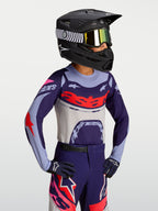 Alpinestars Jeugd Supertech Dyna jersey, paarse en rode lichtgewicht motocrossjersey voor kinderen, atletische race-fit op model met helm en crossbril.