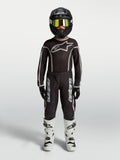 Alpinestars Maillot et Ensemble Fluid Apex V2 Junior, tenue de motocross noire et argentée avec bottes blanches.