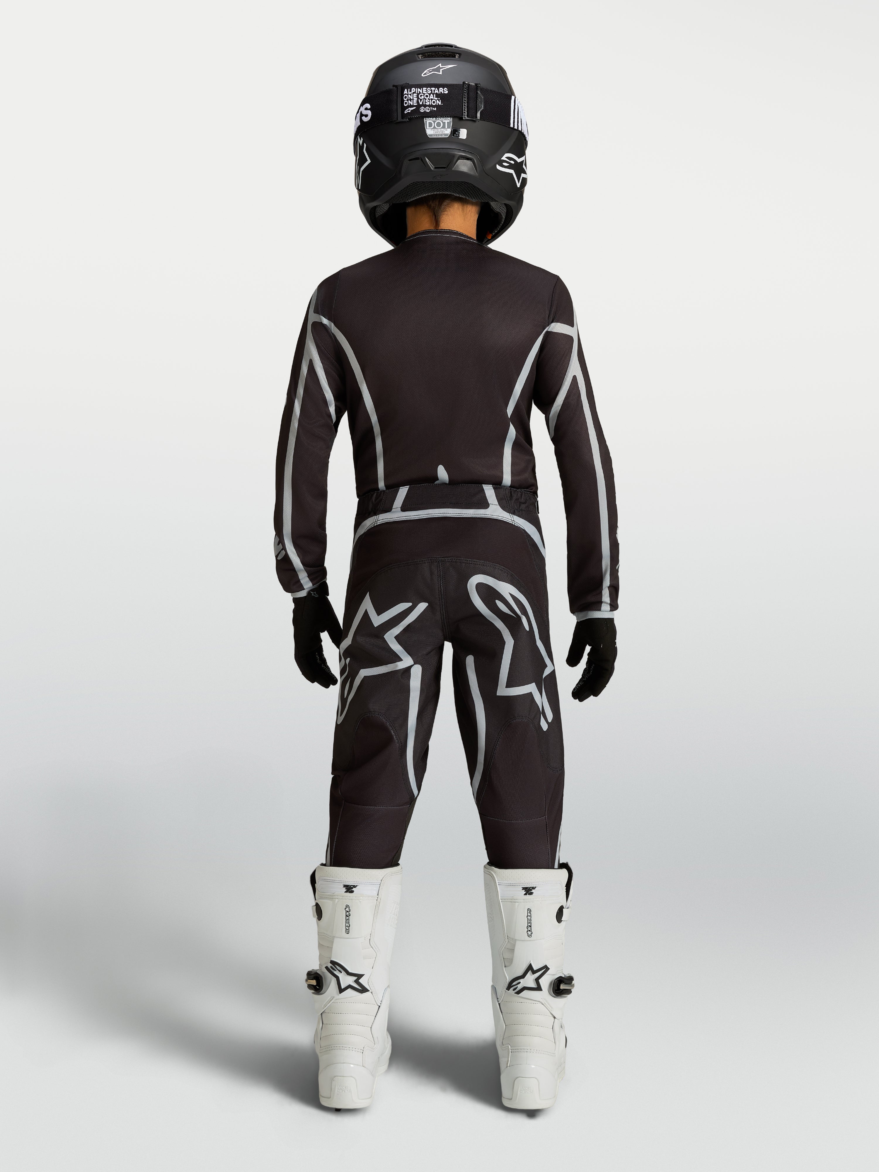 Alpinestars Youth Fluid Apex V2 Jersey and Gear Set, black and silver motocross kit with white boots, rear view.