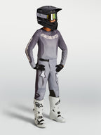 Alpinestars Youth Fluid Amber Gear Set, gray motocross jersey and pants with white racing boots and black helmet.