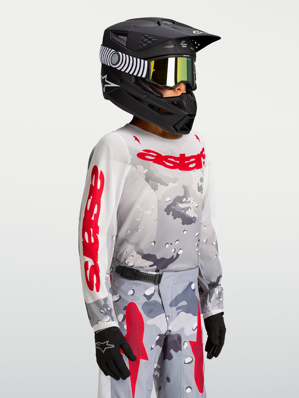 Alpinestars Fluid Jugend-Trikot Lone 2027, Motocross-Trikot in Grau Camo und Rot, getragen von einem Model mit Helm.