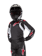 Jugend 2024 Racer Lucent Trikot, Motocross-Trikot, Schwarz, Weiß und Rot, getragen von einem jugendlichen Fahrer mit schwarzem Helm und passender Hose, mit roten Stern-Logos und weißen Grafikakzenten, Performance-Offroad-Bekleidung für Dirt-Bike-Rennen