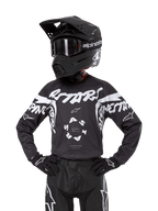 Alpinestars Youth 2024 Racer Hana Jersey, maillot de motocross pour enfant, noir et blanc, design graphique avec logos, porté avec un casque et des gants assortis, équipement de protection tout-terrain