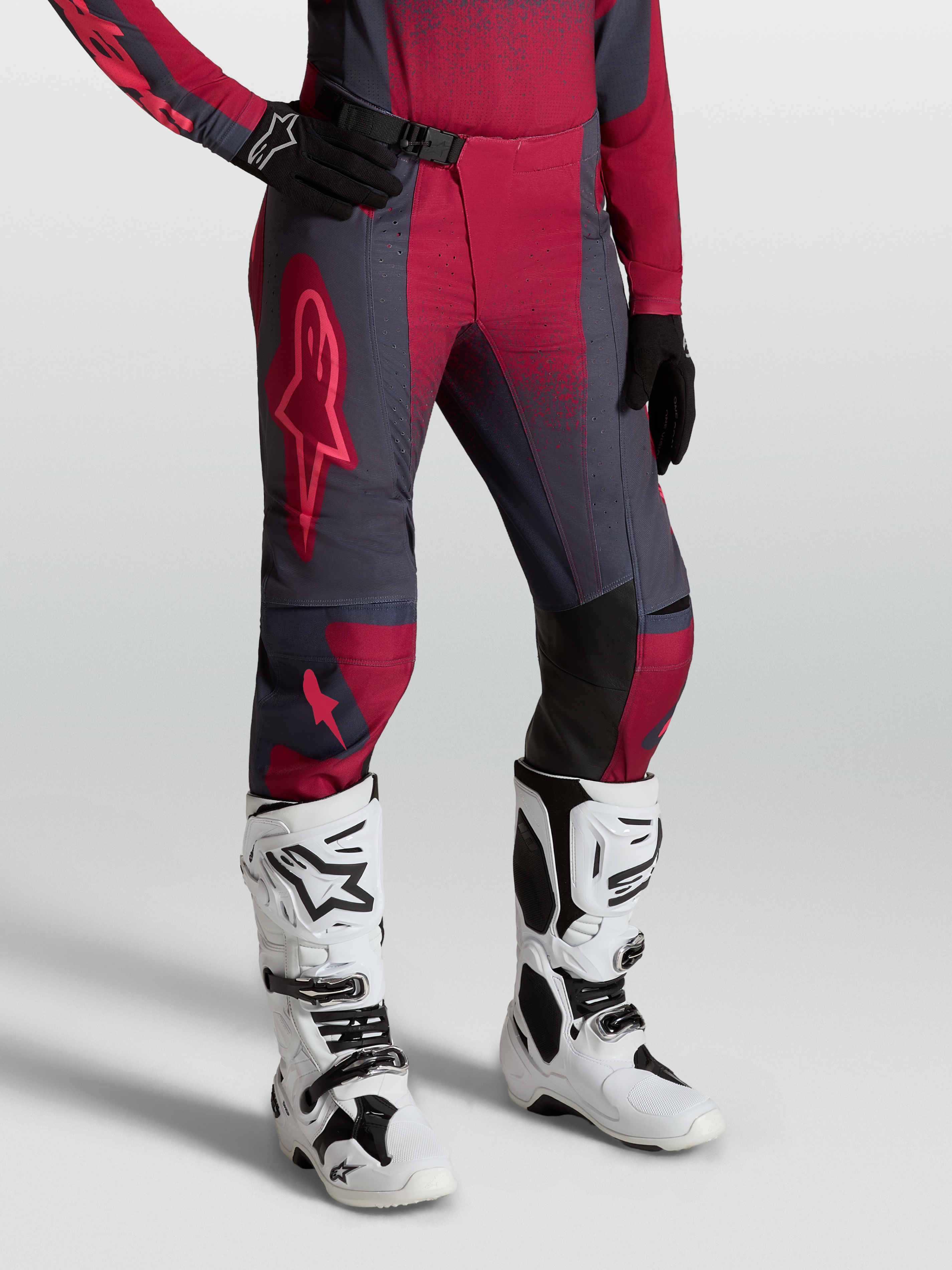 Alpinestars Stella Techstar Swan, pantalon de motocross pour femme, rouge et gris, porté avec bottes Tech 10 blanches.