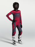 Maillot et ensemble Stella Techstar Swan d'Alpinestars, tenue de motocross femme rouge et gris foncé avec bottes blanches.