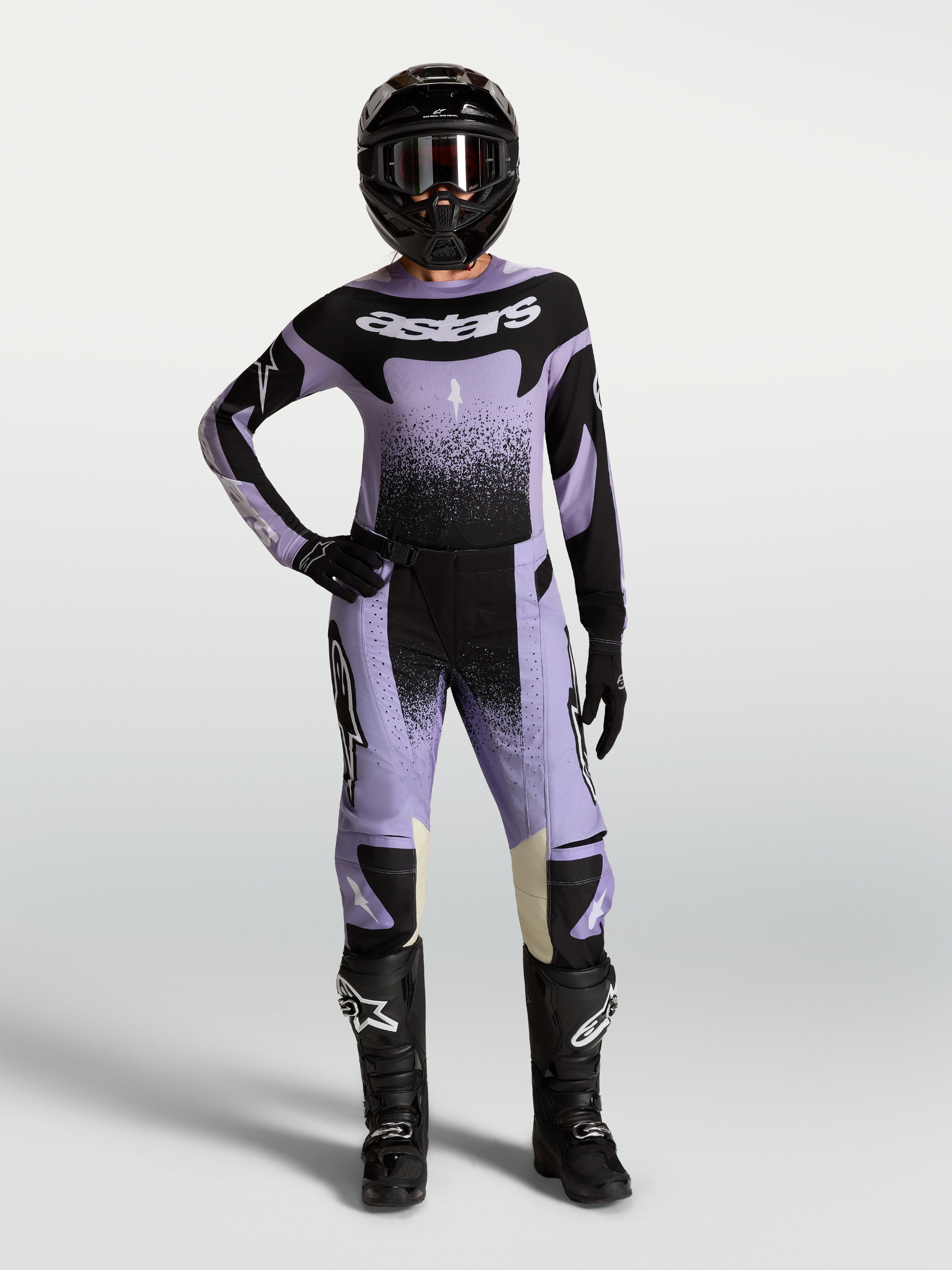 Alpinestars Stella Techstar Swan Gear Set und Trikot, Motocross-Bekleidungsset für Damen, Lila und Schwarz, mit Swan-Grafik, athletische Rennpassform, Frontansicht am Model mit Helm und Stiefeln.