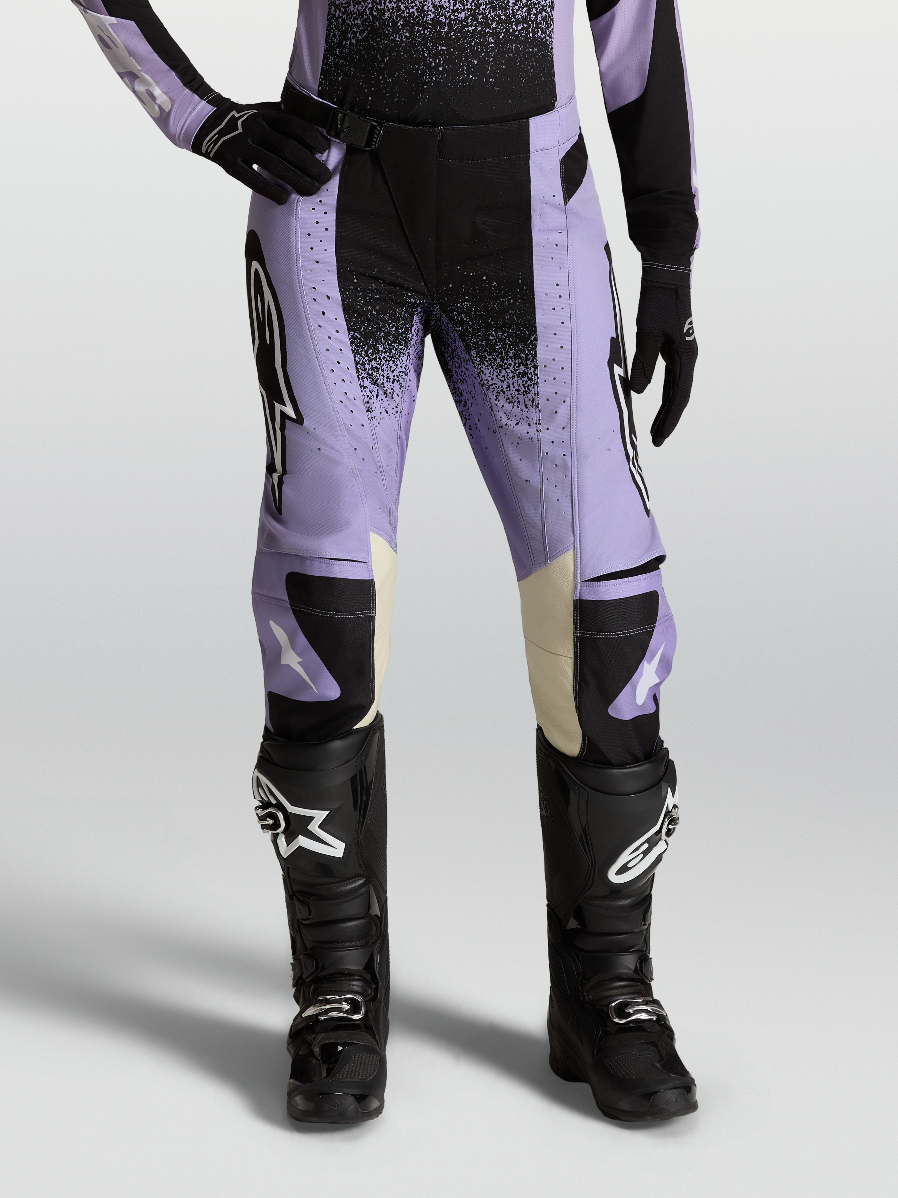 Alpinestars Stella Techstar Swan, pantalon de motocross pour femme, violet et noir avec accents en cuir crème, porté avec des bottes tout-terrain noires