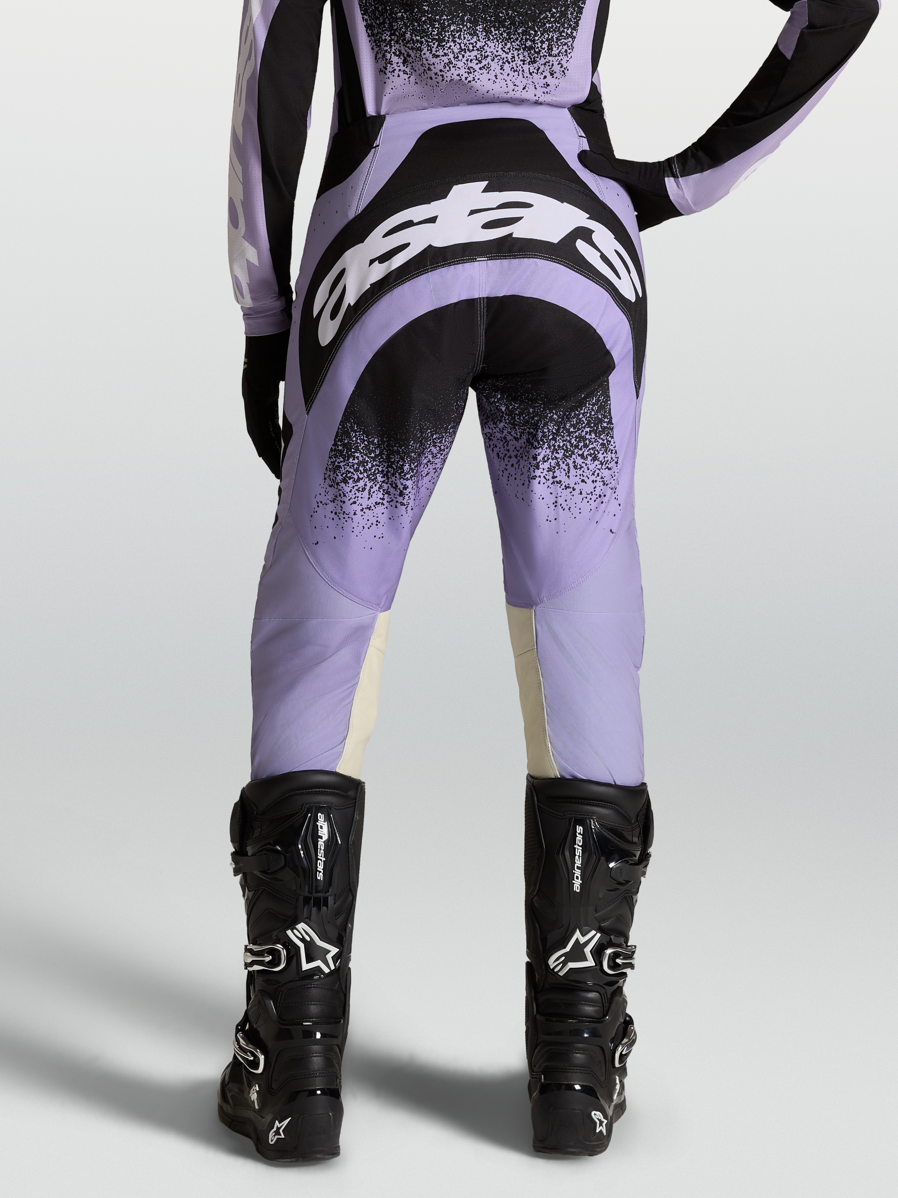 Alpinestars Stella Techstar Swan Broek, dames motorcrossbroek, paars en zwart, met zwarte motorlaarzen.