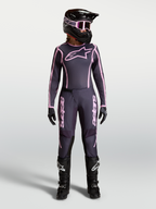 Alpinestars Stella Fluid Apex V2 motocross-kledingset voor dames, grijs en roze, gedragen met helm en laarzen.