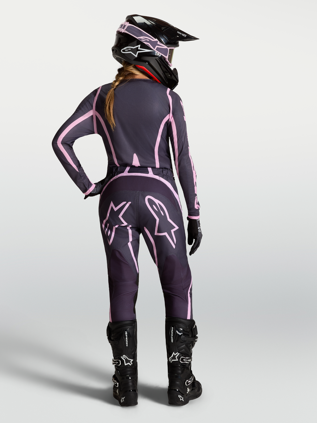 Alpinestars Stella Fluid Apex V2 dames-motorcrossbroek, grijs en roze, achteraanzicht op rijder met bijpassende uitrusting.