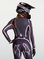 Alpinestars Stella Fluid Apex V2 jersey, dames motocross-outfit, grijs en roze, gedragen met passende helm.