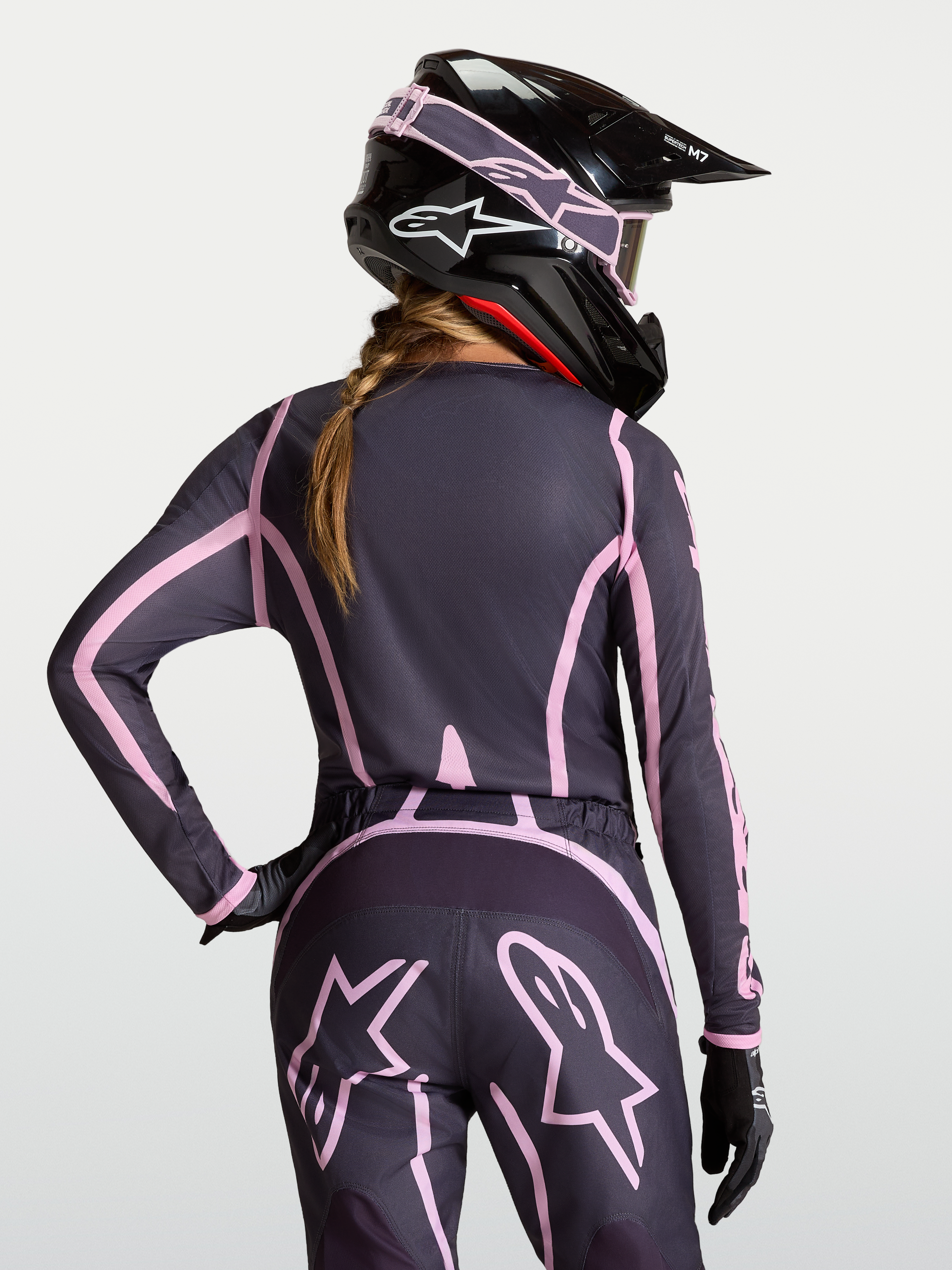 Alpinestars Stella Fluid Apex V2 jersey, dames motocross-outfit, grijs en roze, gedragen met passende helm.