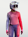 Alpinestars Stella Fluid Kepler jersey, dames motocross-top in paars en rood, athletische pasvorm, vochtafvoerend polyfabric, gedragen met bijpassende helm en handschoenen.