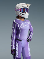 Alpinestars 2026 Stella Fluid Apex gear-set voor dames, paars en lavendelkleurig motocross-shirt en crossbroek, gedragen door een rijder met een witte helm en paarse crossbril, voorzien van opvallende witte Alpinestars-branding en logo's