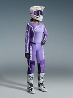 Alpinestars 2026 Stella Fluid Apex Gear Set, paars en lavendel, vrouwelijke motorcrossrijder met bijpassende jersey en broek, witte helm met paarse crossbril, witte en zwarte laarzen, zwarte en paarse handschoenen, complete performance-outfit voor dames off-road racing