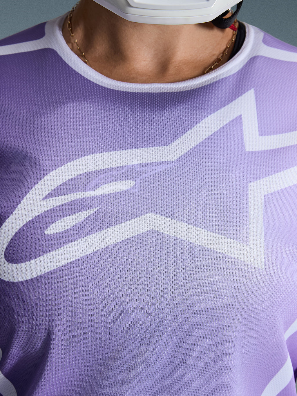 Alpinestars 2026 Stella Fluid Apex Jersey, close-up van de borst, paars met witte graphics, groot wit Astars-logo op mesh polyfabric constructie