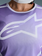Alpinestars 2026 Stella Fluid Apex Jersey, close-up van de borst, paars met witte graphics, groot wit Astars-logo op mesh polyfabric constructie