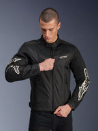 Veste Alpinestars T-Dyno Air, noire, veste de moto en textile avec panneaux en maille 3D et logos blancs sur les manches, portée par un mannequin fermant le zip frontal, style de conduite urbain