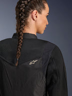 Alpinestars Stella T-Dyno Air Jacket, zwarte damesmotorjas, close-up achteraanzicht met 3D-meshpanelen op het juk en de bovenrug voor luchtstroom, voorzien van een klein wit sterlogo, gedragen door een model met gevlochten haar