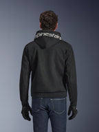 Alpinestars Chrome Superairflow Hoodie, sweat à capuche de moto noir, vue de dos avec marquage Alpinestars blanc sur la capuche, construction en mesh technique 3D, porté avec un jean bleu foncé et des gants noirs, équipement de conduite urbaine ventilé