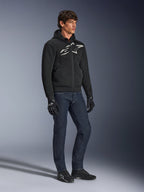 Hoodie Alpinestars Chrome Superairflow, noir avec logo blanc et gris, construction en textile maille 3D ventilée, porté avec un jean en denim bleu foncé et des gants de moto noirs, style de conduite sport urbain