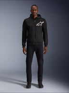 Alpinestars Chrome V2 Sport Hoodie, sweat à capuche de moto noir et blanc, avec un grand logo Alpinestars blanc sur la poitrine, fermeture éclair frontale et capuche, porté par un mannequin debout avec un pantalon et des bottes noirs, équipement de protection de style urbain.