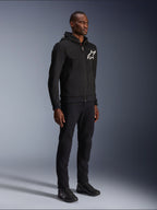 Alpinestars Chrome V2 Sport Hoodie, sweat à capuche de moto noir avec logo étoile blanc, porté par un mannequin homme avec un pantalon noir et des baskets de moto assortis, équipement de conduite au style urbain