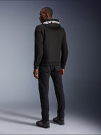 Alpinestars Chrome V2 Sport Hoodie, noir, vue de dos montrant le marquage Alpinestars blanc sur la capuche, porté avec un pantalon noir et des chaussures de moto, vêtement de moto urbain décontracté à la silhouette athlétique