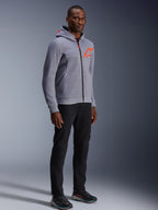 Alpinestars Chrome V2 Sport Hoodie, Gray Heather und Red Fluo, getragen von einem männlichen Model mit schwarzer Hose und dunklen Sportschuhen, mit einem leuchtend orangefarbenen Stern-Logo auf der Brust und Kapuze, lässige urbane Motorradbekleidung