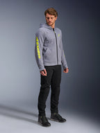 Alpinestars Chrome V2 Sport Hoodie, gris chiné et jaune fluo, porté par un mannequin homme avec un pantalon noir et des chaussures de moto noires, avec un logo jaune vif sur la manche et la poitrine, équipement de moto urbain et décontracté