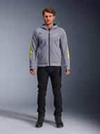 Sweat à capuche Alpinestars Chrome V2 Sport, gris chiné avec accents jaune fluo, vêtement de moto urbain, présenté avec un pantalon noir et des chaussures de moto noires, polaire technique avec marquage jaune vif sur les manches et la poitrine, style urbain décontracté pour la conduite