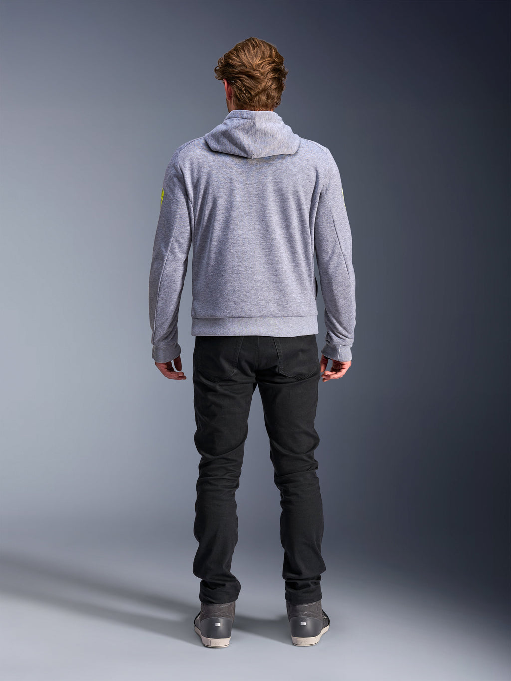 Alpinestars Chrome V2 Sport Hoodie, gris chiné jaune fluo, vue de dos d'un équipement de moto urbain, sweat à capuche en polaire technique porté avec un pantalon noir, doté d'accents jaune fluo sur les manches.