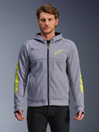 Alpinestars Chrome V2 Sport Hoodie, gris chiné et jaune fluo, vue de face sur modèle, sweat à capuche de moto en polaire technique avec fermeture éclair frontale, logo étoile jaune fluo sur la poitrine et marquage sur les manches, équipement de conduite urbaine décontracté
