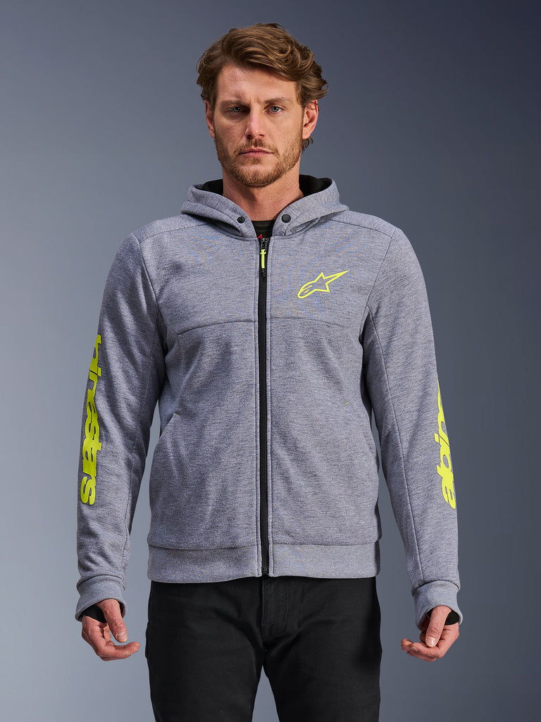 Alpinestars Chrome V2 Sport Hoodie, Grau meliert und Fluo-Gelb, Vorderansicht am Modell, Tech-Fleece Motorrad-Kapuzenjacke mit Reißverschluss, neongelbes Stern-Logo auf der Brust und Markenschriftzug an den Ärmeln, lässige urbane Motorradbekleidung