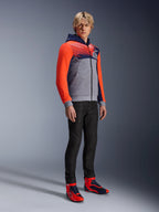 Sweat à capuche sport Alpinestars MM93 Chrome V2, sweat de moto urbain, corps gris chiné avec poitrine bleu marine et manches rouge fluo, logo 93 sur la poitrine, porté par un mannequin avec un pantalon noir ajusté et des chaussures de moto montantes coordonnées rouges et bleues, coupe athlétique moderne pour la conduite urbaine