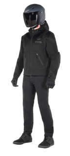 Alpinestars Moflow Air Tech Hoodie, sweat à capuche de moto urbain, noir, porté par un pilote avec un casque noir mat, des gants noirs et un pantalon de moto, doté d'une construction intégrale en maille pour une ventilation optimale, de poches zippées et de logos discrets sur la poitrine, design décontracté pour la conduite urbaine par temps chaud.