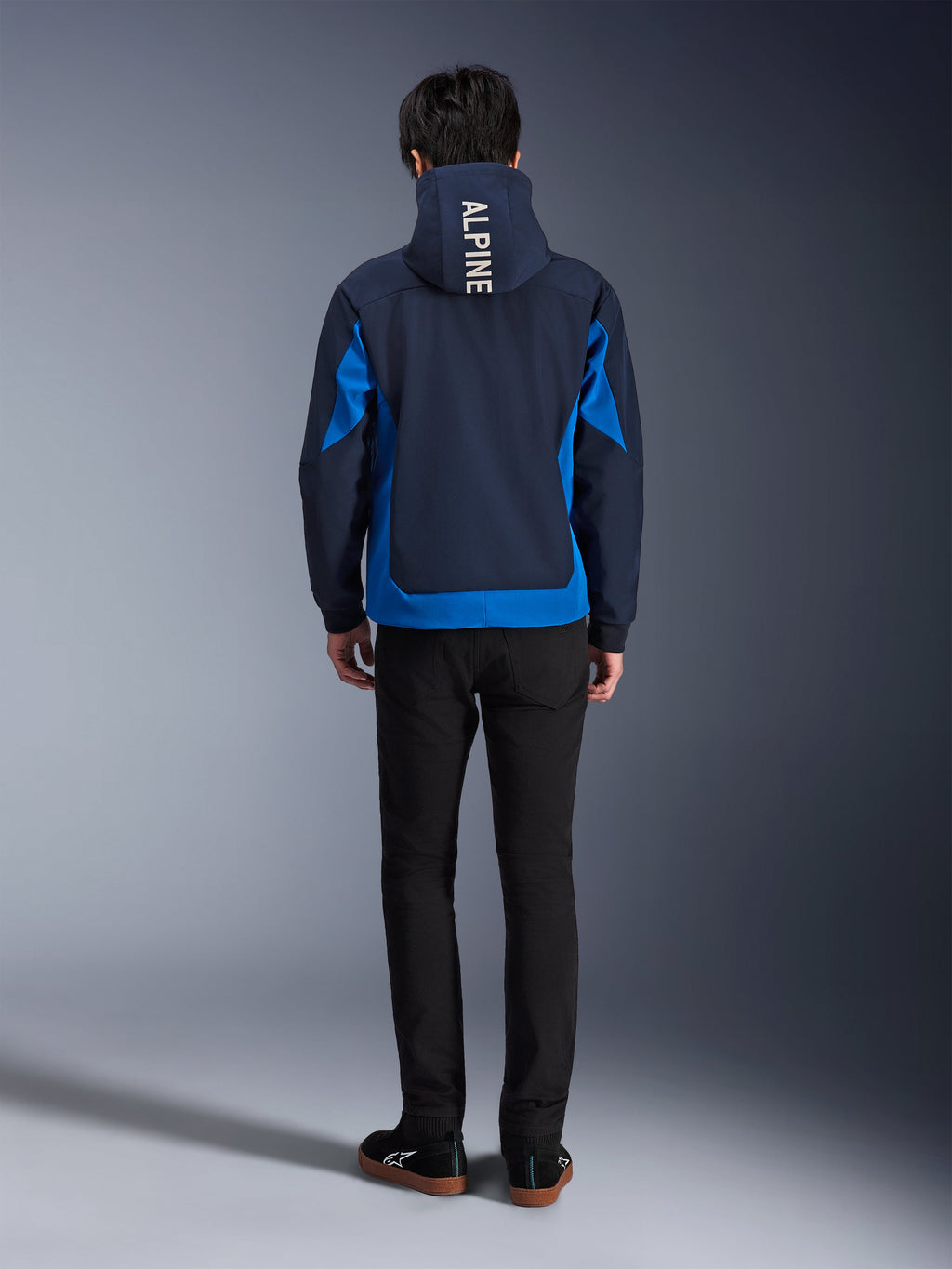 Alpinestars Radium Tech Hoodie, Night Navy und Royal Blue, Rückansicht mit vertikalem 'ALPINE'-Branding auf der Kapuze, königsblauen Seiteneinsätzen und Saum, lässiger urbaner Motorrad-Hoodie mit winddichtem 3L-Shell, getragen mit schwarzer Hose
